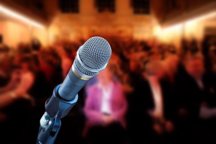 Close up van een microfoon voor een vol conferentiecentrum